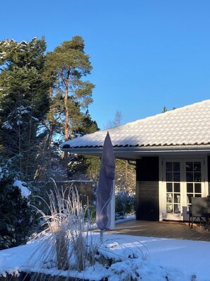 A house with a snow-covered roof, a covered patio area, and a view of tall trees. - Perfect base near beach and shops (Væggerløse)