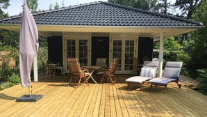 A covered outdoor deck with wooden furniture, including chairs and a table, and a patio umbrella. - Perfect base near beach and shops (Væggerløse)