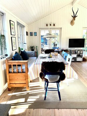 A spacious room with a long dining table, a wooden bench, a mounted animal head, and a television. - Perfect base near beach and shops (Væggerløse)