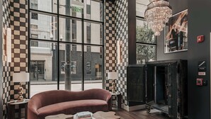 Een modern interieur met een groot raam, een ruitpatroon op de muur, een open haard en een bank.