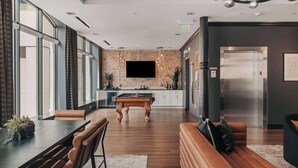 Een modern interieur met een eethoek, een woonkamer met een bank, een keuken met een bakstenen muur, en een lift.