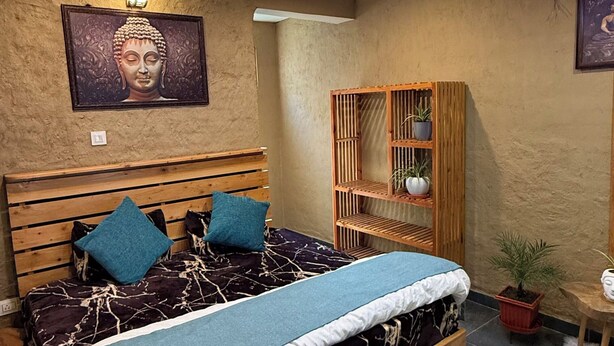 A modern bedroom with a wooden bed, a blue accent wall, and a ceiling light fixture. - Karma Yatri Mudhouse Kasol (Bhuntar)