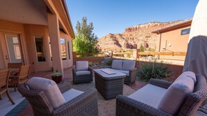 An outdoor patio with wicker furniture and a view of a mountainous landscape. - Upscale 4 bedroom family home near Zion w pool & hot tub (Kanab)