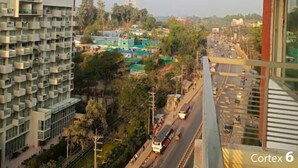 A high-rise building with multiple balconies, a busy street below, and a distant communication tower. - World Beach Resort Cox's Bazar (Cox's Bazar)