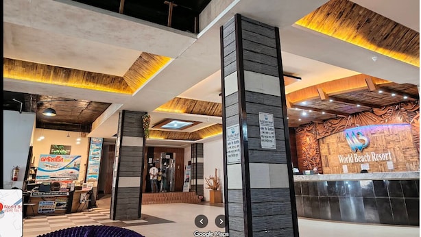 A modern hotel lobby with a reception desk, a sign for 'World Beach Resort', and a large wooden accent wall. - World Beach Resort Cox's Bazar (Cox's Bazar)
