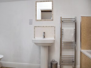 A bathroom with a pedestal sink, a mirror, a towel rack, and a trash can. - Holly Tree Barn - UK49607 (Minshull Vernon, near Nantwich)