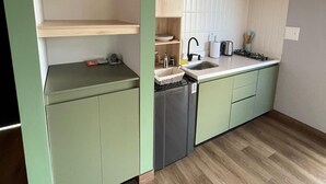 A modern kitchen with green cabinets, a wooden countertop, and a built-in dishwasher. - Glamping Boreal (Guatapé)
