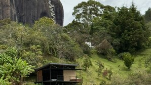 A small cabin on a grassy hill with a large rock formation in the background. - Glamping Boreal (Guatapé)