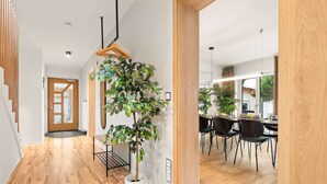 Un interior moderno con una escalera de madera, una planta en maceta y un comedor con sillas y una mesa.
