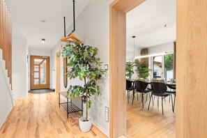 Ein modernes Interieur mit einer Holztreppe, einem Topfpflanzen und einem Essbereich mit Stühlen und Tisch.