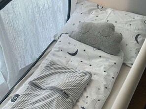 A bed with a white sheet featuring a star and moon pattern, a grey cloud-shaped pillow, and striped bedding. - Holiday home with terrace whirlpool, families welcome! (Ruhpolding)