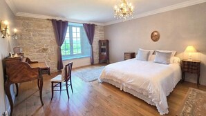 Ein Schlafzimmer mit einem großen Bett, einem Schreibtisch mit Stuhl, einer Chandelier und einer Steinwand.