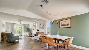 A spacious living area with a dining table, chairs, and a fireplace. - Retro Vegas Getaway - Just 2 Miles to The Vegas Strip with a Pool & Hot Tub (Las Vegas)
