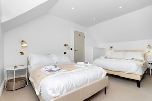 Une chambre d’hôtel moderne avec deux lits, une petite table de chevet, une chaise et un grand miroir.