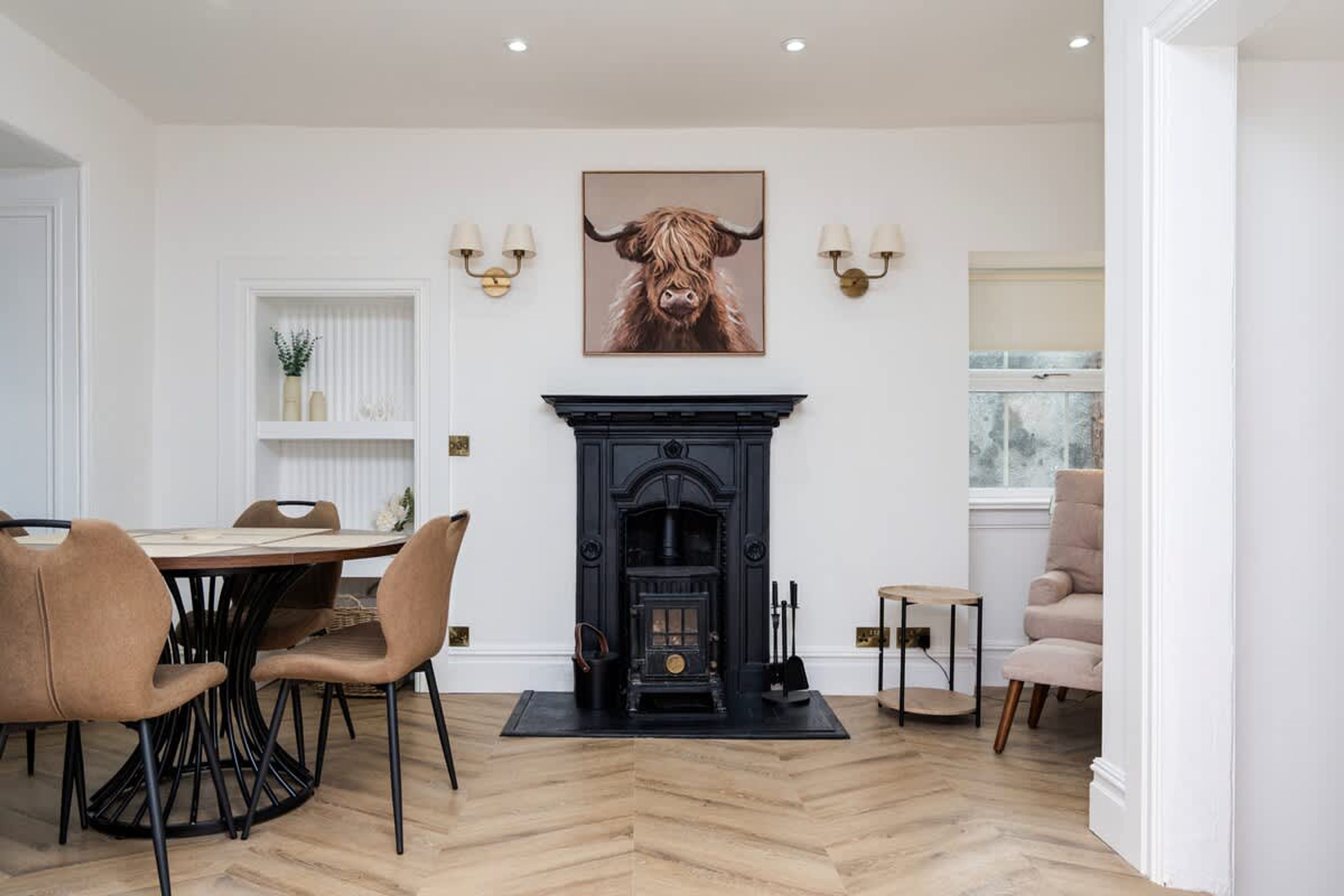 A dining area with a black fireplace, a table with chairs, and a framed picture above the fireplace.