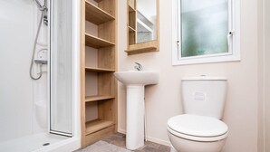 Un bagno con doccia, lavandino, WC e mensole in legno.
