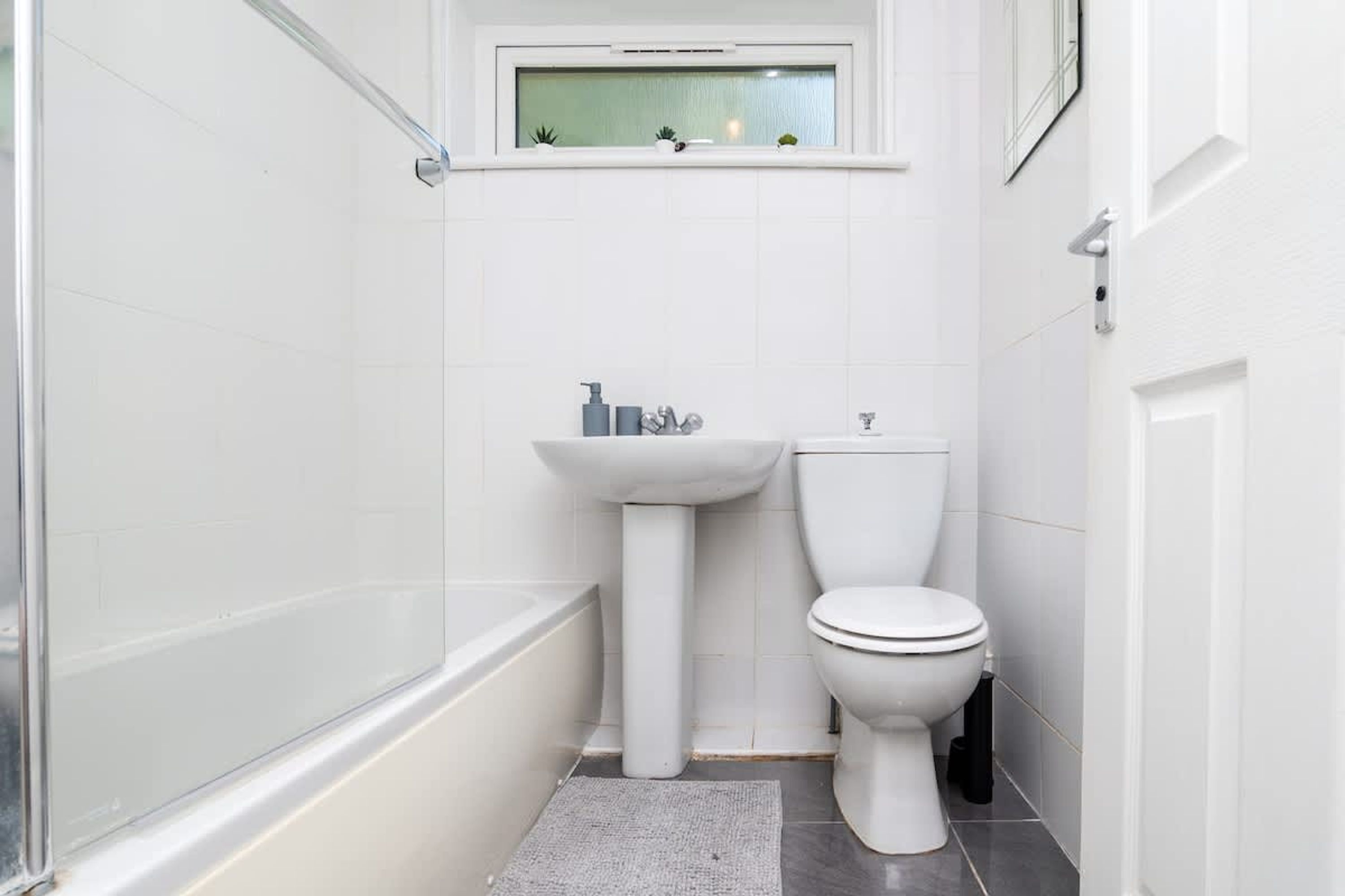A small, white bathroom with a bathtub, a sink, and a toilet.