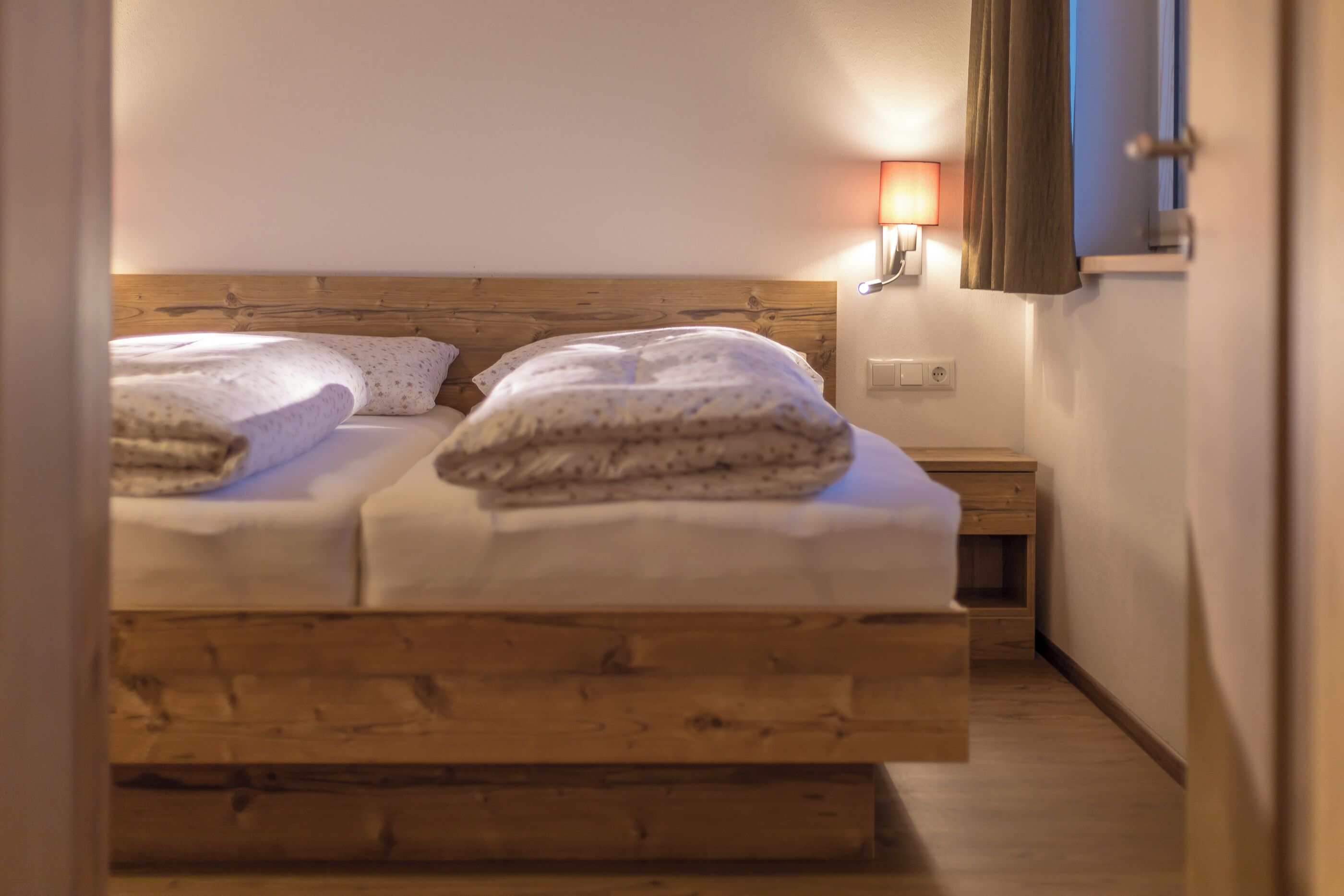 Une chambre à coucher avec une tête de lit en bois, une table de chevet et une lampe fixée au mur.