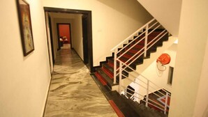 Ένας διάδρομος με μαρμάρινο δάπεδο που οδηγεί σε μια σκάλα με κόκκινα σκαλοπάτια και λευκά κάγκελα.