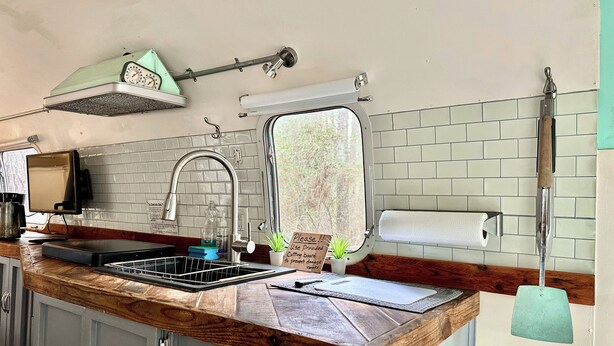 A kitchen with a wooden countertop, a sink, a window, and a hanging towel rack.