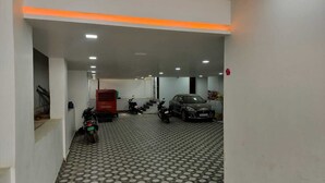 Eine Parkgarage mit gemustertem Boden, mehreren parkenden Autos und Motorrädern.