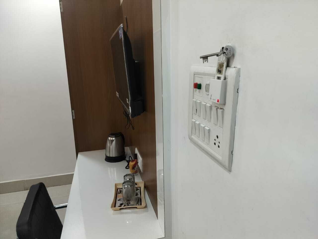 Una pequeña kitchenette con cafetera, hervidor y un enchufe en la pared.