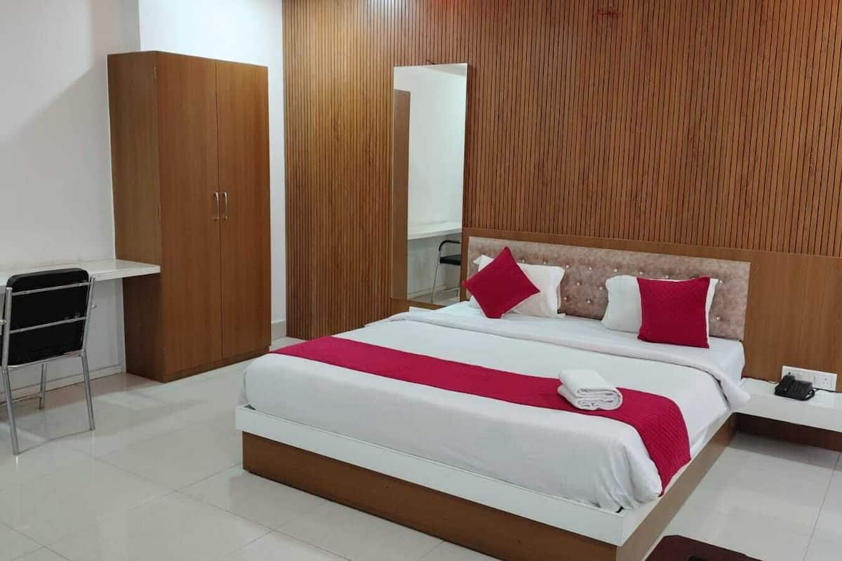 Een hotelkamer met een bed, bureau, stoel en een kast.