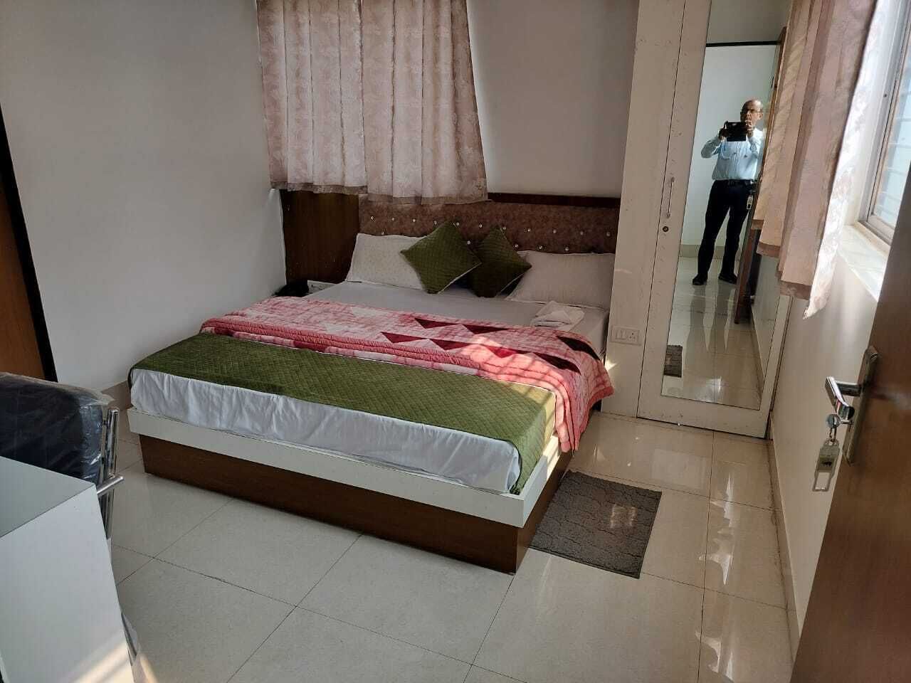 A bedroom with a bed, a mirror, and a door.