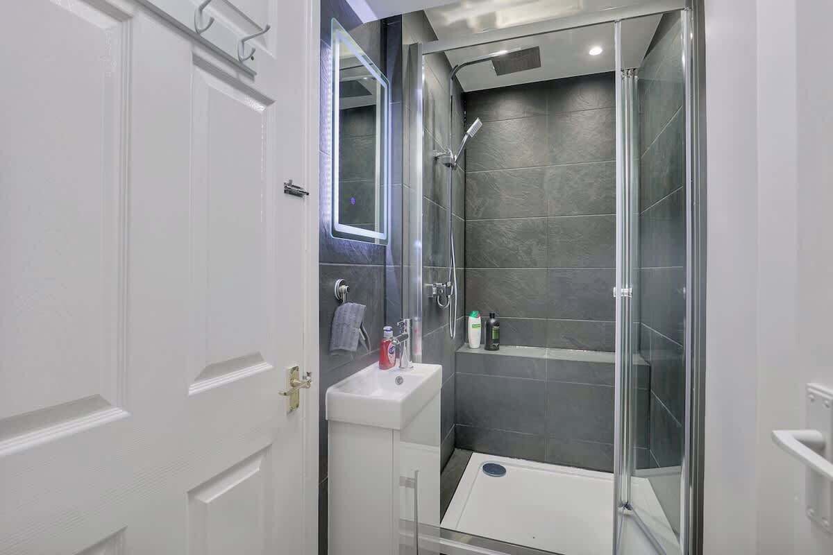 A modern bathroom with a glass-enclosed shower, a white sink, and a mirror.