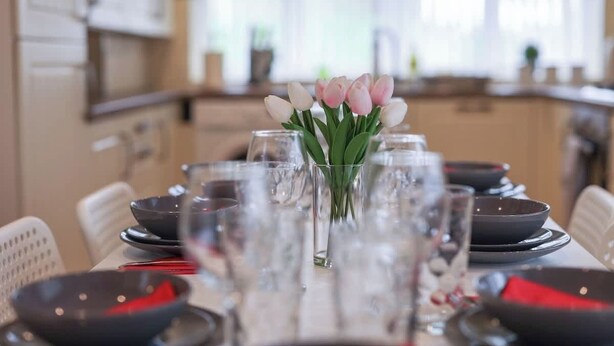 A dining table set with clear glasses, black plates, and red napkins. - Spacious 4 Bedroom House With Parking (Gateshead)