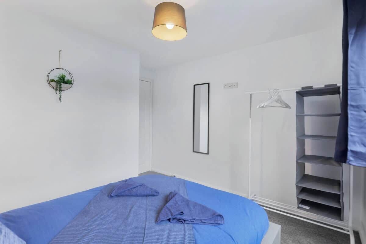 A bedroom with a bed, a hanging plant, a wardrobe, and a mirror.
