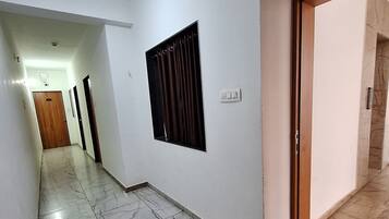 Un pasillo con piso de mármol, una ventana con cortinas y una puerta que da a otra habitación.