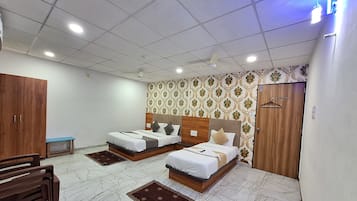 Una habitación de hotel con dos camas, un armario, un escritorio y una silla.