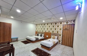 A hotel room with two beds, a wardrobe, a desk, and a chair.