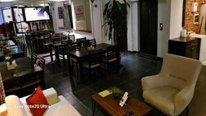 A modern living room with a sofa, armchair, dining area, and a television. - Paperon Butik Otel (Erdemli)