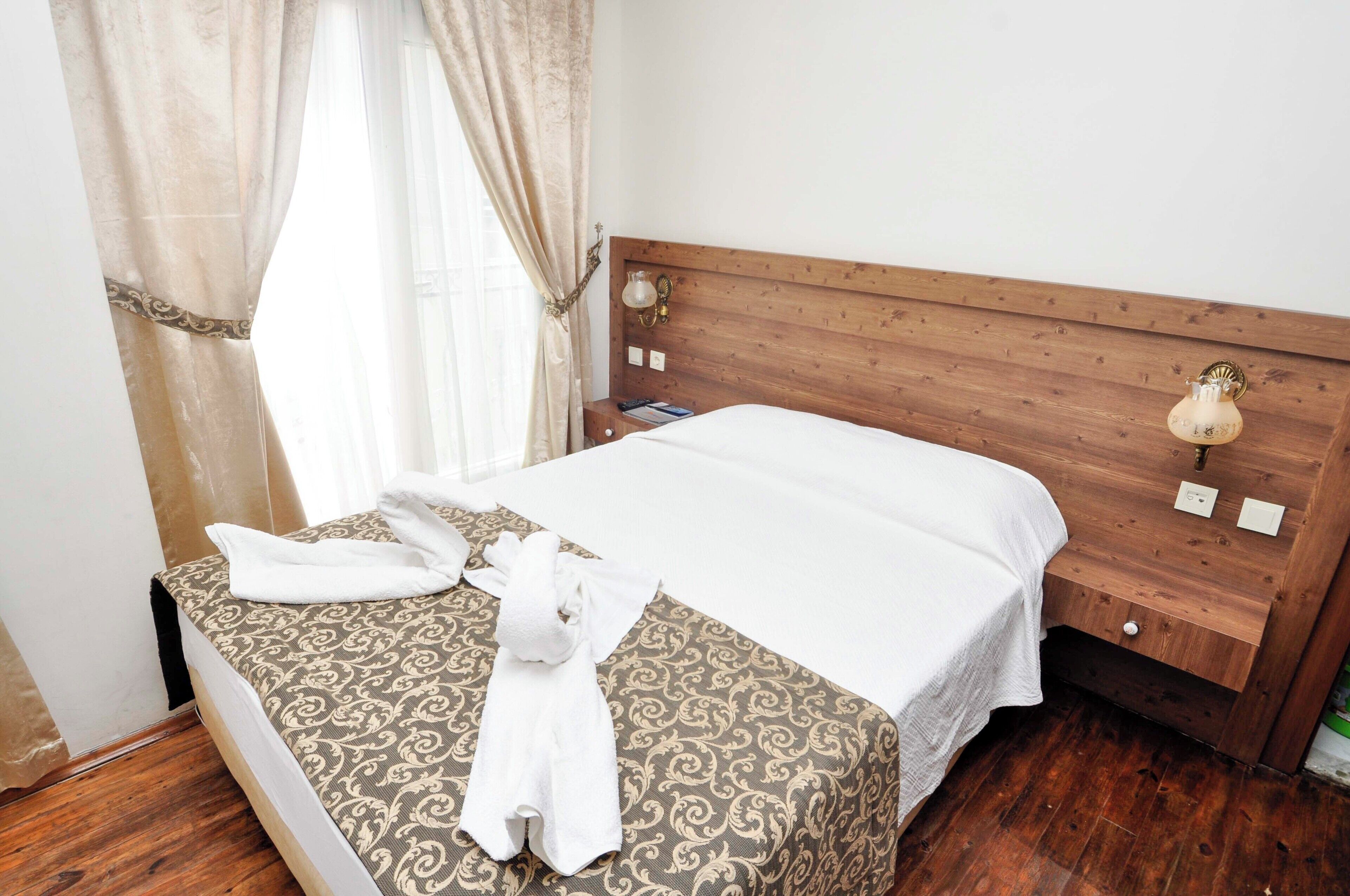 A neatly made bed with a patterned bedspread, a white towel, and a plush pillow.
