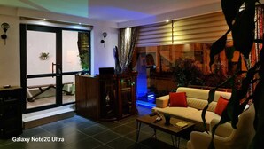 A modern living room with a sofa, coffee table, and a glass door leading to an outdoor area. - Paperon Butik Otel (Erdemli)