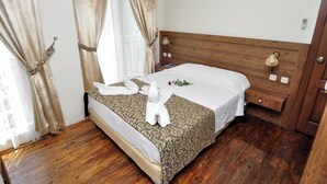 A neatly made bed with a patterned bedspread, a wooden headboard, and a bedside table with a lamp. - Paperon Butik Otel (Erdemli)