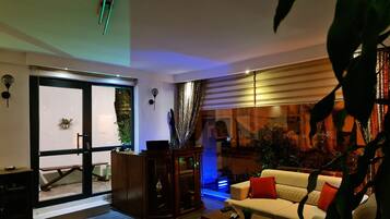 A modern living room with a sofa, coffee table, and a glass door leading to an outdoor area.