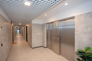 A modern hallway with a patterned ceiling, a long corridor, and a set of elevators. - Liiiving in Porto - Campus Blue Studio (Porto)