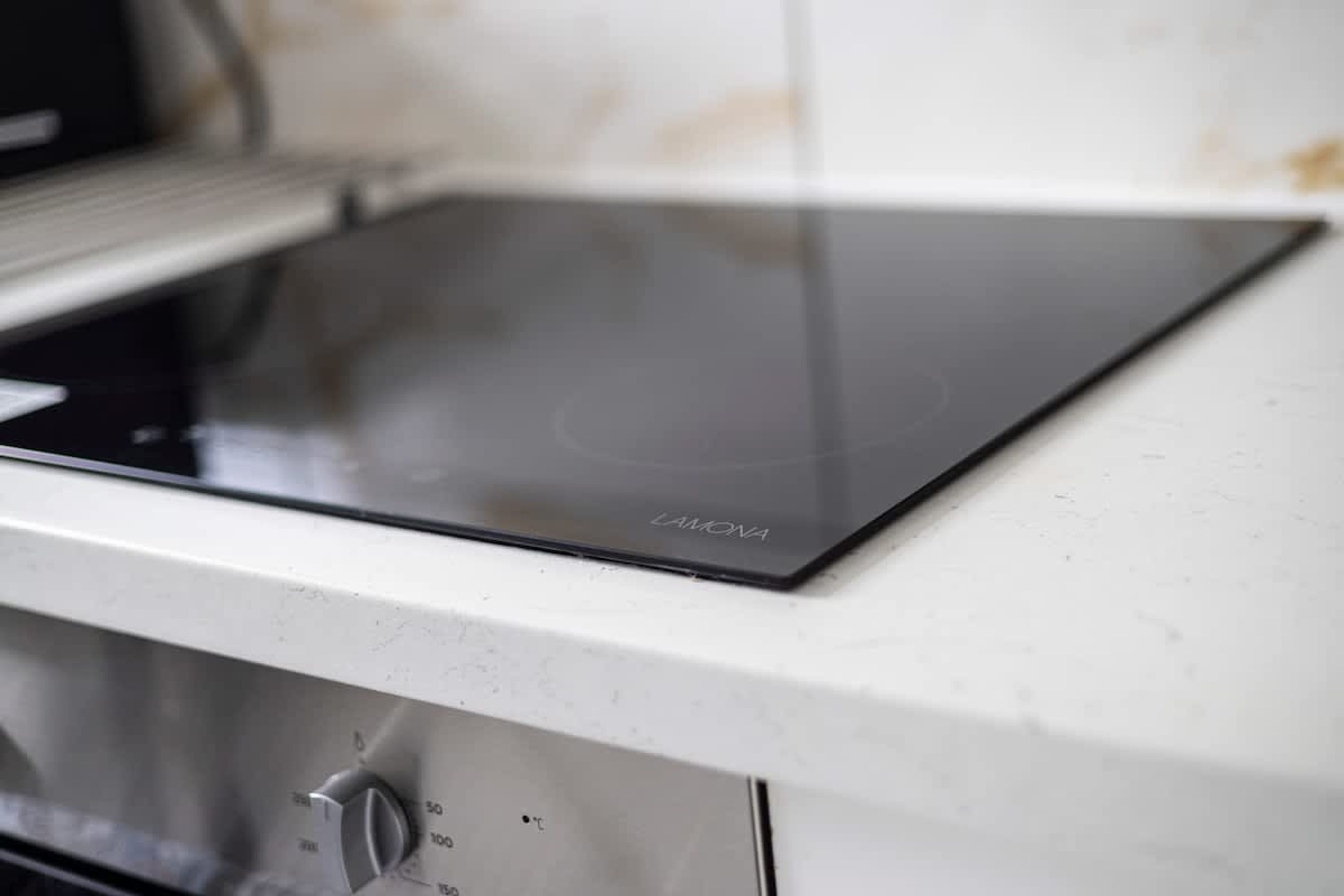 Een keuken met een wit aanrecht en een zwart inductiefornuis.