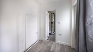 A hallway with a glass shower door, a white door, and a grey curtain. - 3bedroom 2 Bathroom House-free Parking 5 Beds (Barrow-in-Furness)