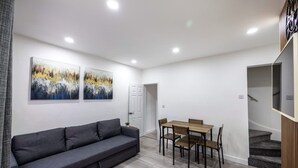 A modern living room with a gray sofa, wooden dining table, and two abstract paintings on the wall. - 3bedroom 2 Bathroom House-free Parking 5 Beds (Barrow-in-Furness)