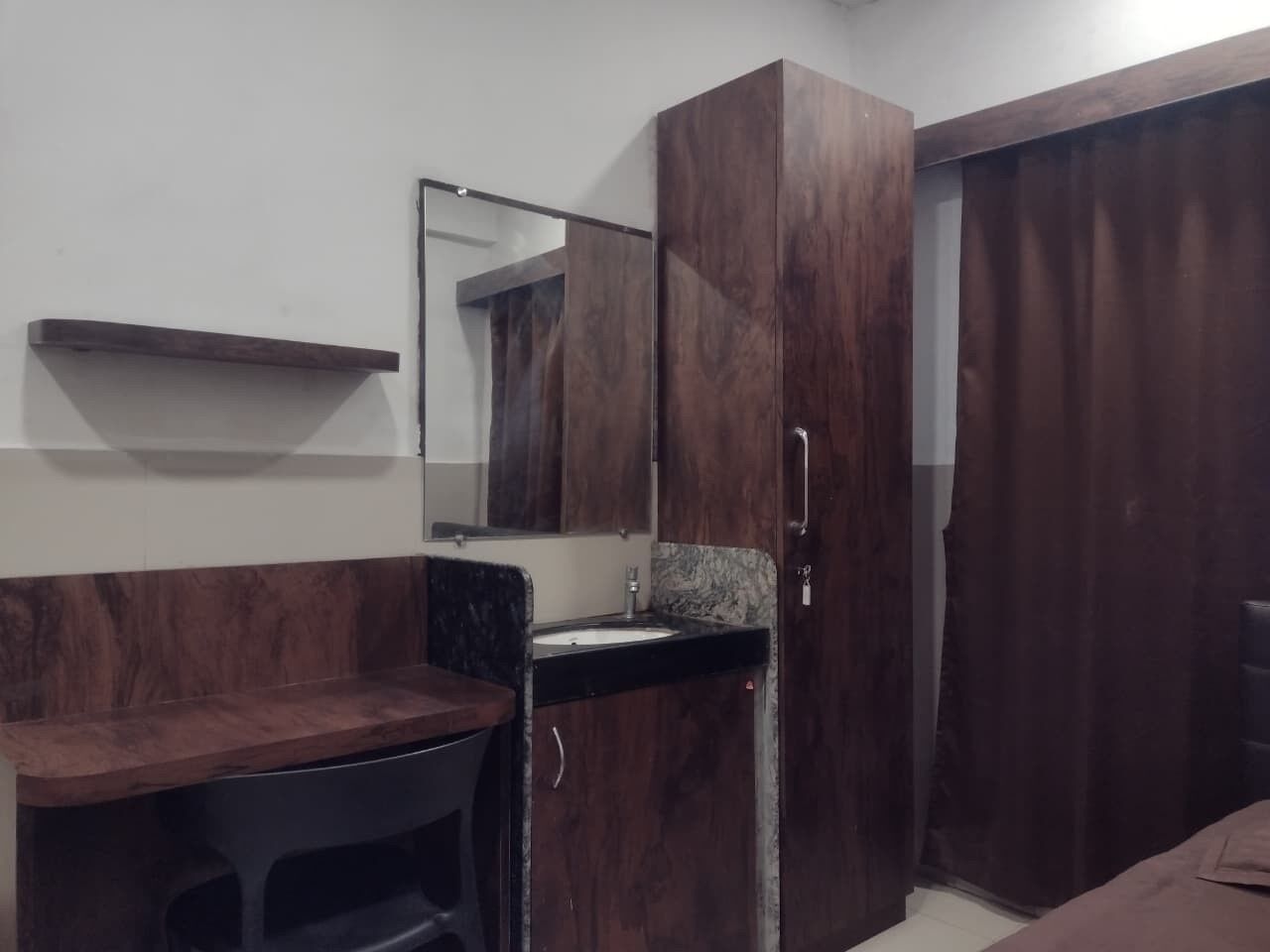 A small, compact room with a wooden vanity, a mirror, a sink, and a wardrobe.