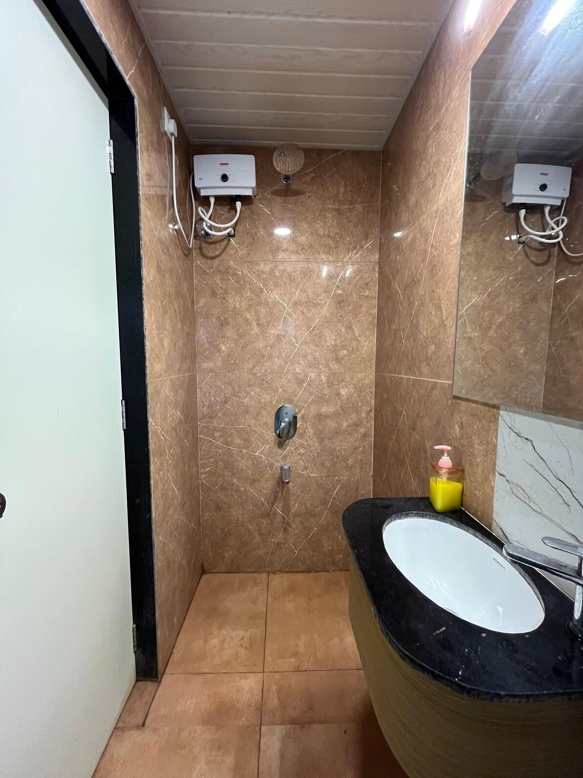 Un baño con piso de mármol, lavamanos negro y un espejo.