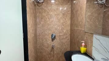 Un baño con piso de mármol, lavamanos negro y un espejo.