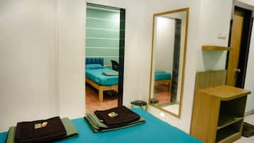 A hotel room with a bed, a mirror, a small table, and a shelf.