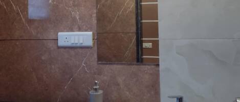 Un bagno con una parete in marmo, un lavabo con piano nero, uno specchio e un dispenser per sapone.