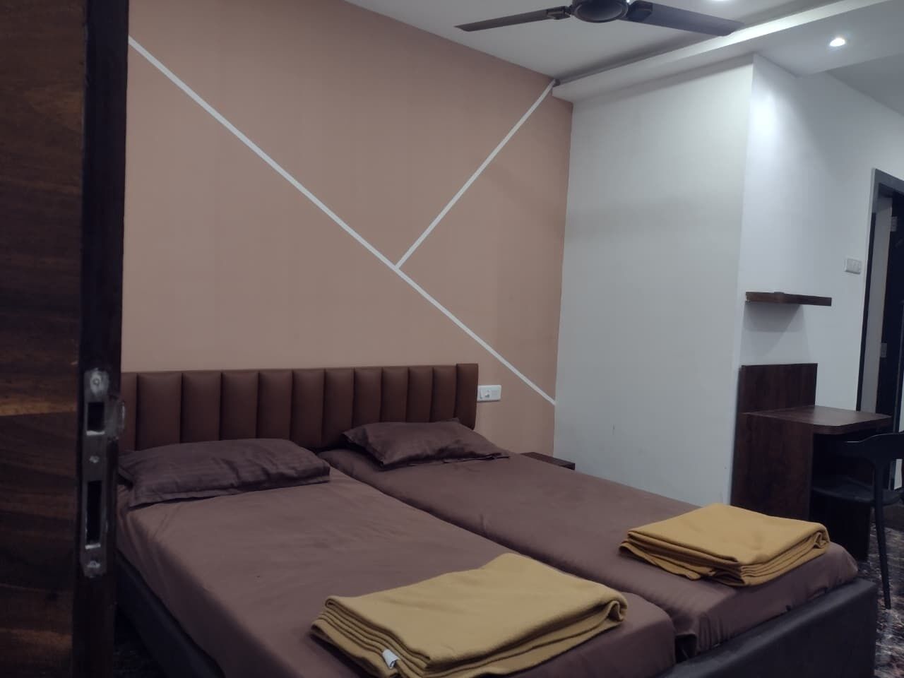 Una cama doble con cabecera, dos almohadas y una manta doblada sobre la cama.