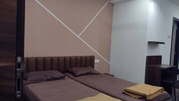 Una cama doble con cabecera, dos almohadas y una manta doblada sobre la cama.
